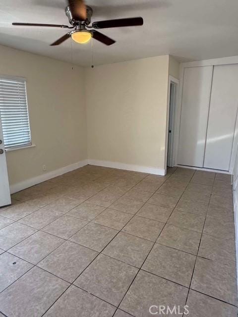 tiled spare room with ceiling fan