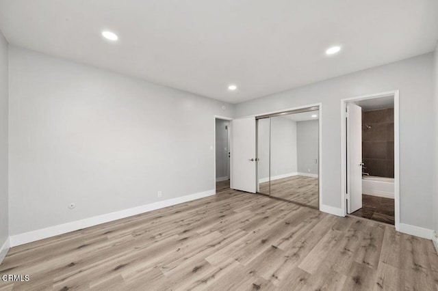 unfurnished bedroom featuring recessed lighting, a closet, ensuite bath, light wood-type flooring, and baseboards