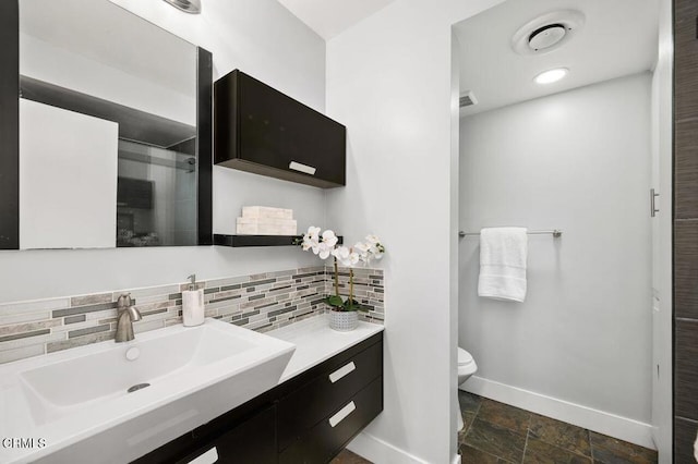 full bath featuring backsplash, toilet, stone finish floor, a shower stall, and baseboards