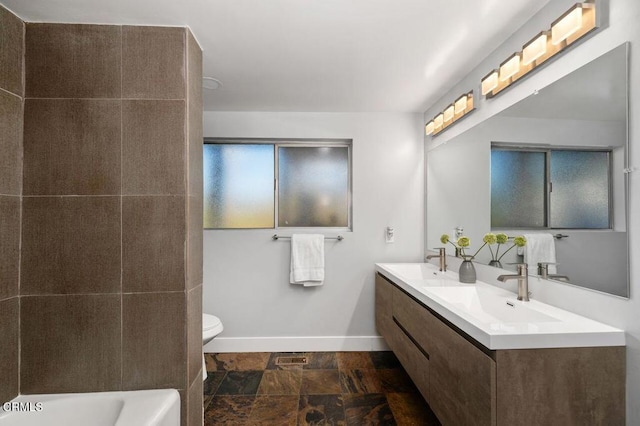 bathroom featuring stone finish floor, a sink, toilet, and baseboards