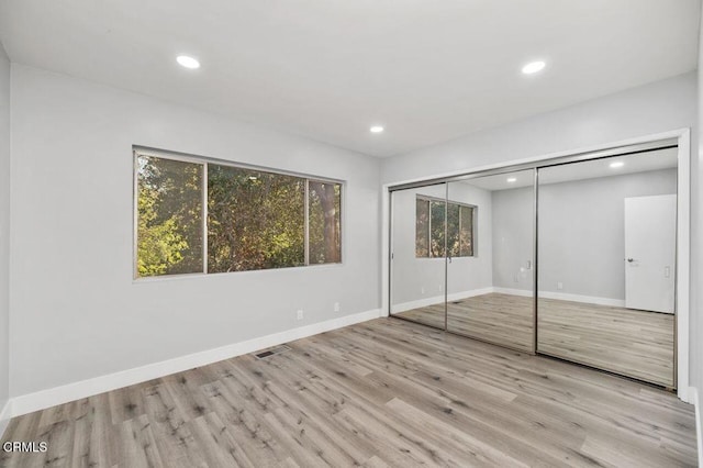 unfurnished bedroom with light wood-style floors, recessed lighting, and baseboards