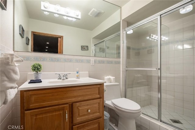 bathroom featuring an enclosed shower, vanity, and tile walls