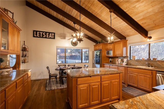 kitchen featuring stainless steel appliances, dark wood-type flooring, sink, decorative light fixtures, and a kitchen island