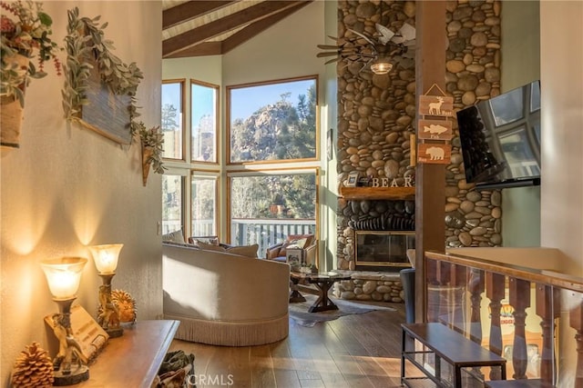 living area featuring a fireplace, wood-type flooring, lofted ceiling with beams, and ceiling fan