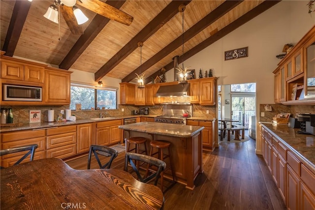 kitchen with a center island, wall chimney exhaust hood, tasteful backsplash, dark hardwood / wood-style floors, and appliances with stainless steel finishes