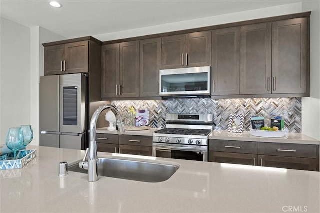 kitchen featuring sink, dark brown cabinetry, stainless steel appliances, and tasteful backsplash