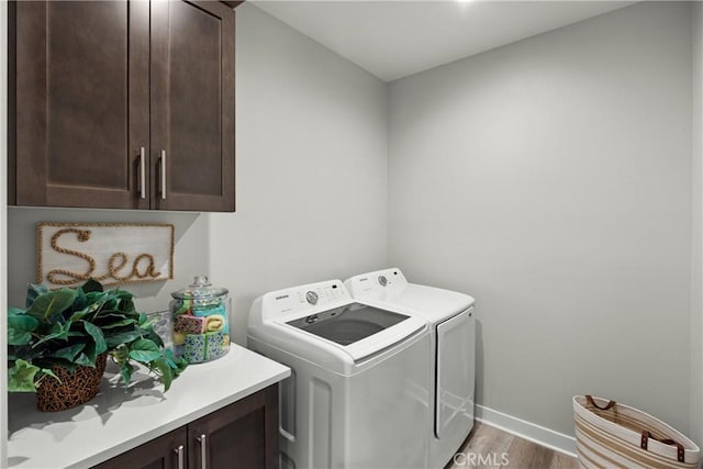 laundry room featuring hardwood / wood-style floors, cabinets, and washing machine and dryer