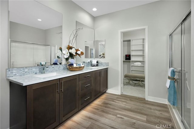 bathroom with backsplash, a shower with door, vanity, and hardwood / wood-style flooring