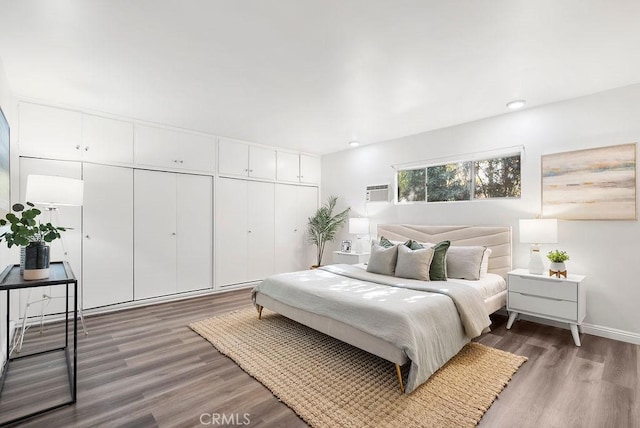 bedroom with a wall unit AC and dark hardwood / wood-style flooring