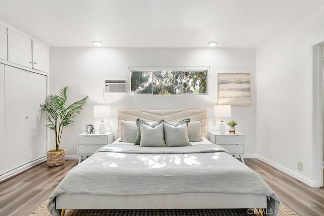 bedroom with an AC wall unit, a closet, and light hardwood / wood-style floors