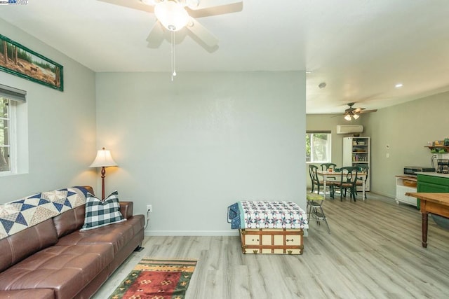 living room with a wall mounted AC, ceiling fan, and light wood-type flooring