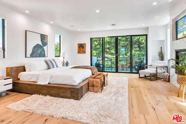 bedroom featuring access to exterior, a fireplace, and light wood-type flooring