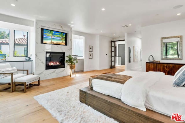 bedroom featuring a premium fireplace and light hardwood / wood-style flooring