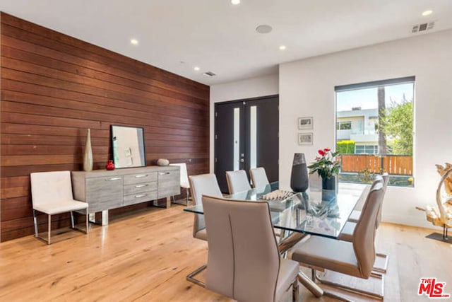 dining area featuring light hardwood / wood-style floors and wooden walls