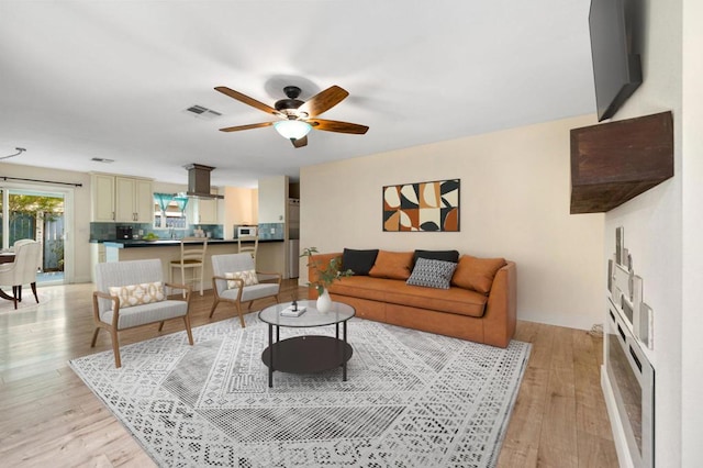 living room with ceiling fan and light hardwood / wood-style flooring