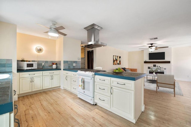 kitchen with tasteful backsplash, island exhaust hood, light hardwood / wood-style floors, kitchen peninsula, and white appliances