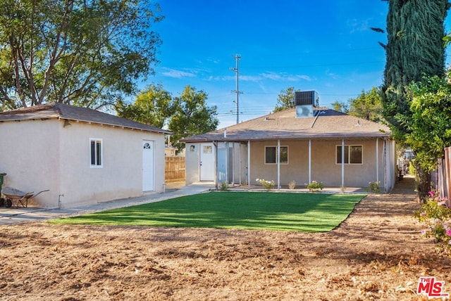 back of property featuring central AC unit and a yard