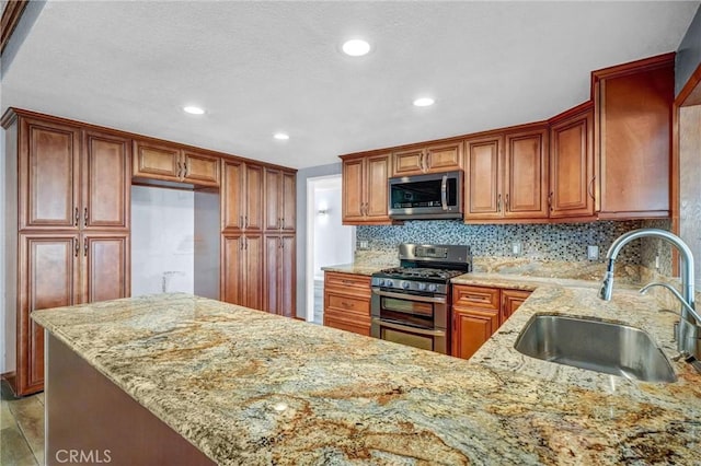 kitchen featuring light stone counters, sink, backsplash, and stainless steel appliances