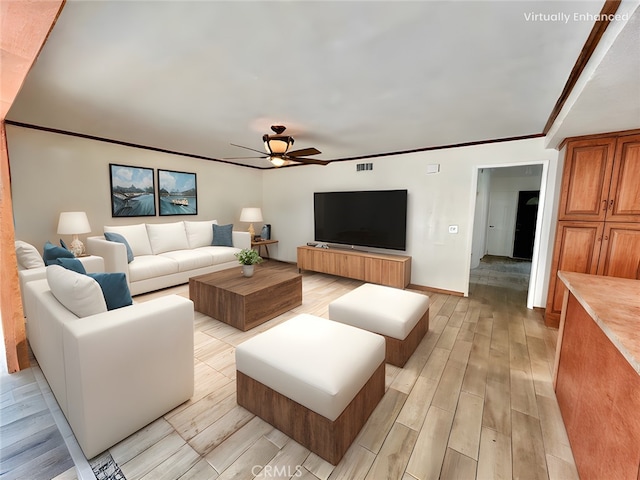 living room featuring ceiling fan, ornamental molding, and light hardwood / wood-style floors