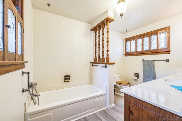 bathroom featuring wood-type flooring, vanity, toilet, and a bathtub