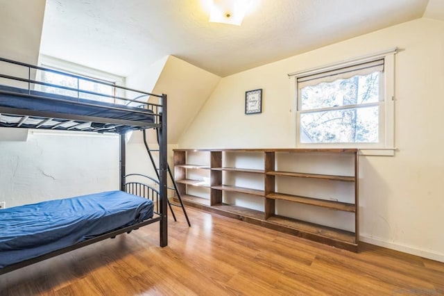 bedroom with hardwood / wood-style flooring, multiple windows, and lofted ceiling