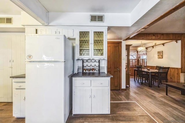 kitchen featuring wooden walls, white cabinets, dark wood-type flooring, and white refrigerator