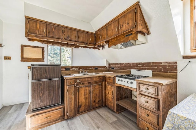 kitchen featuring decorative backsplash, light hardwood / wood-style floors, white gas cooktop, and sink