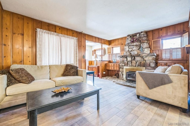 living room with wooden walls, a fireplace, and light wood-type flooring