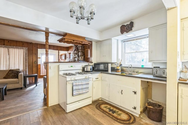 kitchen featuring white cabinets, light wood-type flooring, kitchen peninsula, and gas range gas stove