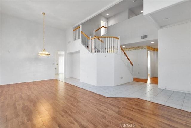 unfurnished living room with a towering ceiling and light wood-type flooring