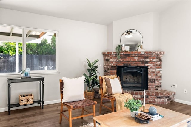 sitting room featuring dark wood-type flooring and a brick fireplace