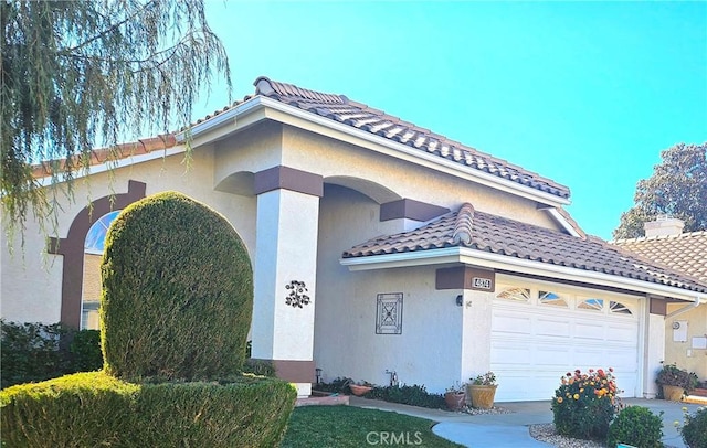 view of front of home featuring a garage, a tile roof, and stucco siding