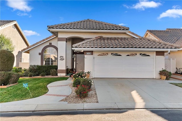 mediterranean / spanish home featuring driveway, a tiled roof, an attached garage, and stucco siding