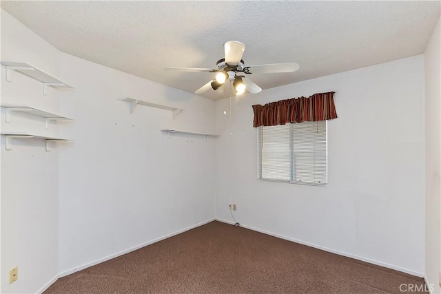 spare room with dark colored carpet, ceiling fan, a textured ceiling, and baseboards