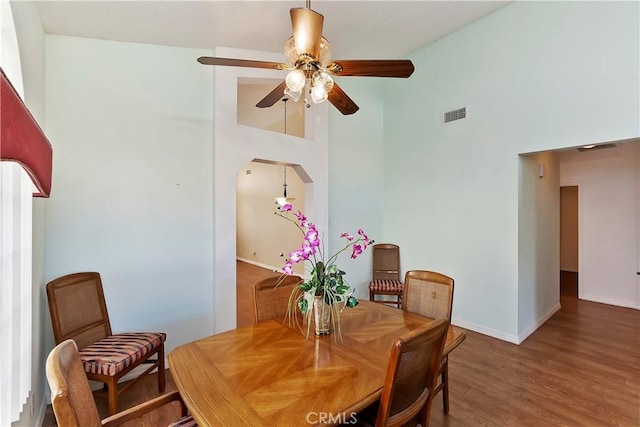 dining space featuring high vaulted ceiling, ceiling fan, baseboards, and wood finished floors