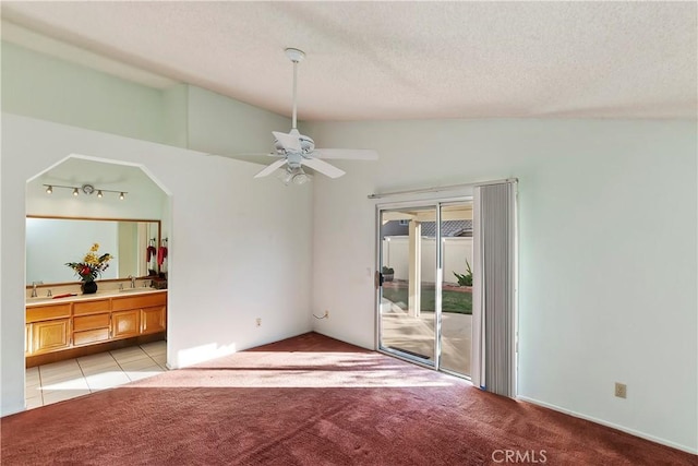 interior space with lofted ceiling, light carpet, a sink, and a textured ceiling