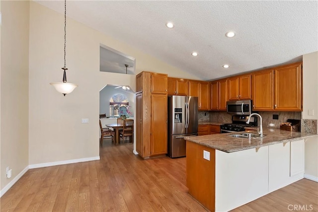 kitchen with stainless steel appliances, lofted ceiling, brown cabinetry, a sink, and a peninsula