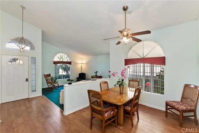 dining space with high vaulted ceiling, ceiling fan, baseboards, and wood finished floors