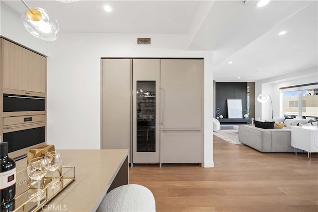 kitchen with double oven, light hardwood / wood-style floors, light brown cabinetry, and fridge