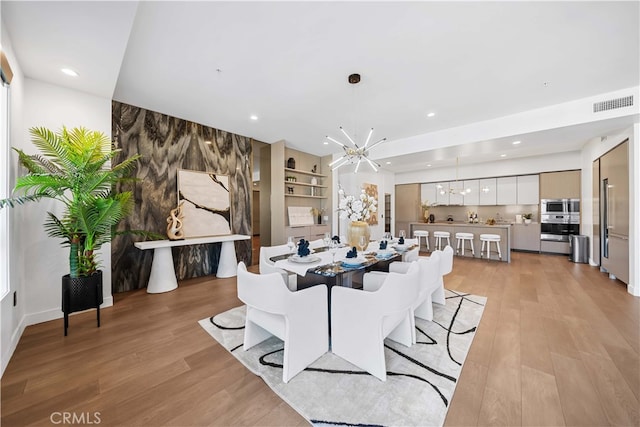 dining space featuring light wood-type flooring and an inviting chandelier