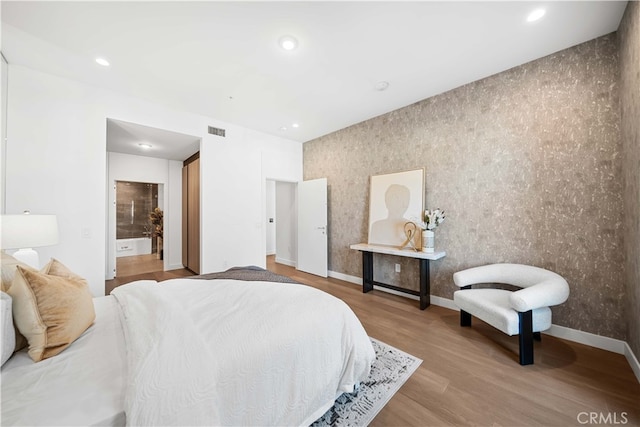 bedroom featuring light hardwood / wood-style floors and ensuite bathroom