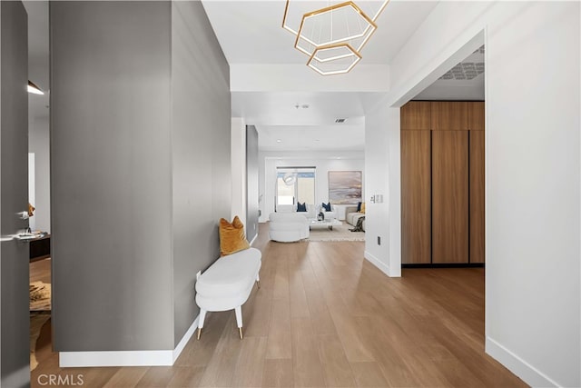 corridor featuring light hardwood / wood-style flooring and an inviting chandelier