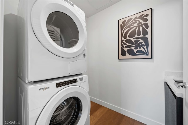 clothes washing area with dark hardwood / wood-style flooring and stacked washer / drying machine