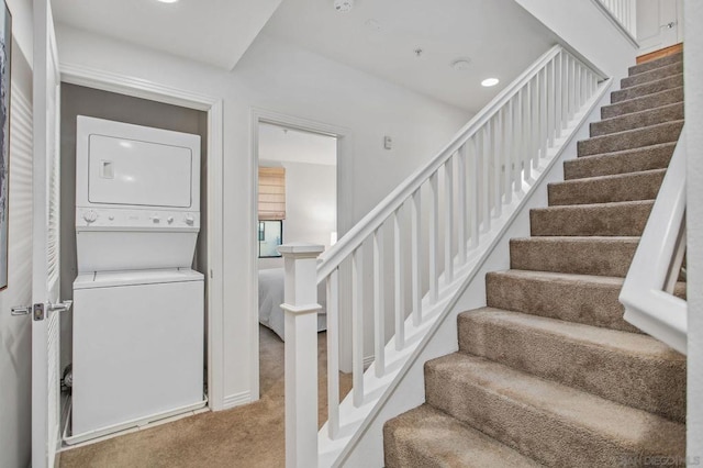 stairs with stacked washer and clothes dryer and carpet flooring