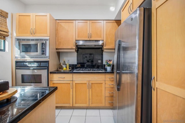 kitchen with light tile patterned floors, backsplash, dark stone countertops, and stainless steel appliances