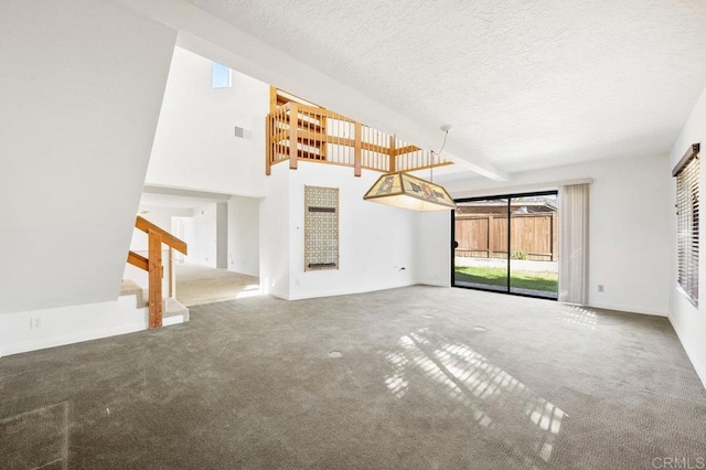 unfurnished living room featuring carpet flooring, beam ceiling, and a textured ceiling