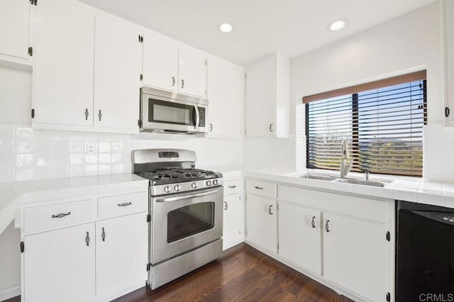 kitchen with tile countertops, white cabinets, sink, appliances with stainless steel finishes, and dark hardwood / wood-style flooring