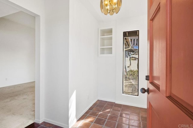 entrance foyer with dark carpet and a notable chandelier