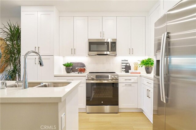 kitchen featuring decorative backsplash, white cabinets, appliances with stainless steel finishes, and sink