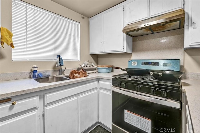 kitchen featuring black gas range oven, sink, white cabinetry, and range hood